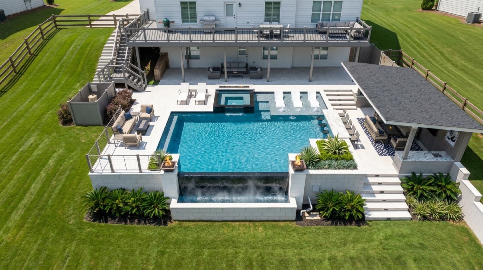 Completed CraftYourPool custom pool with a raised spa, vanishing-edge spillway, and full deck and landscaping